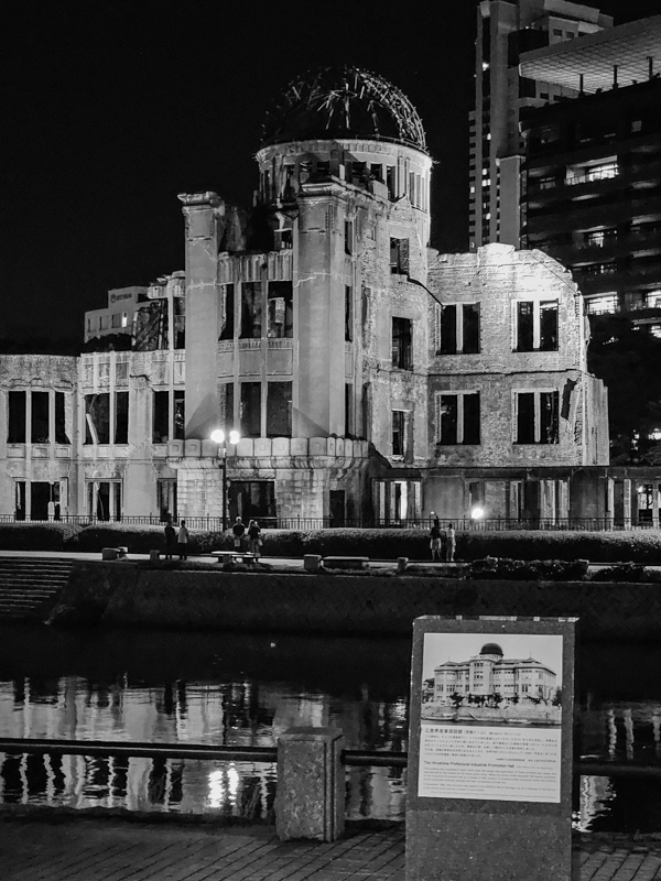 Schwarzweiß Foto einer Ruine mit Spiegelung im Wasser, dahinter ist ein modernen Gebäude erkennbar