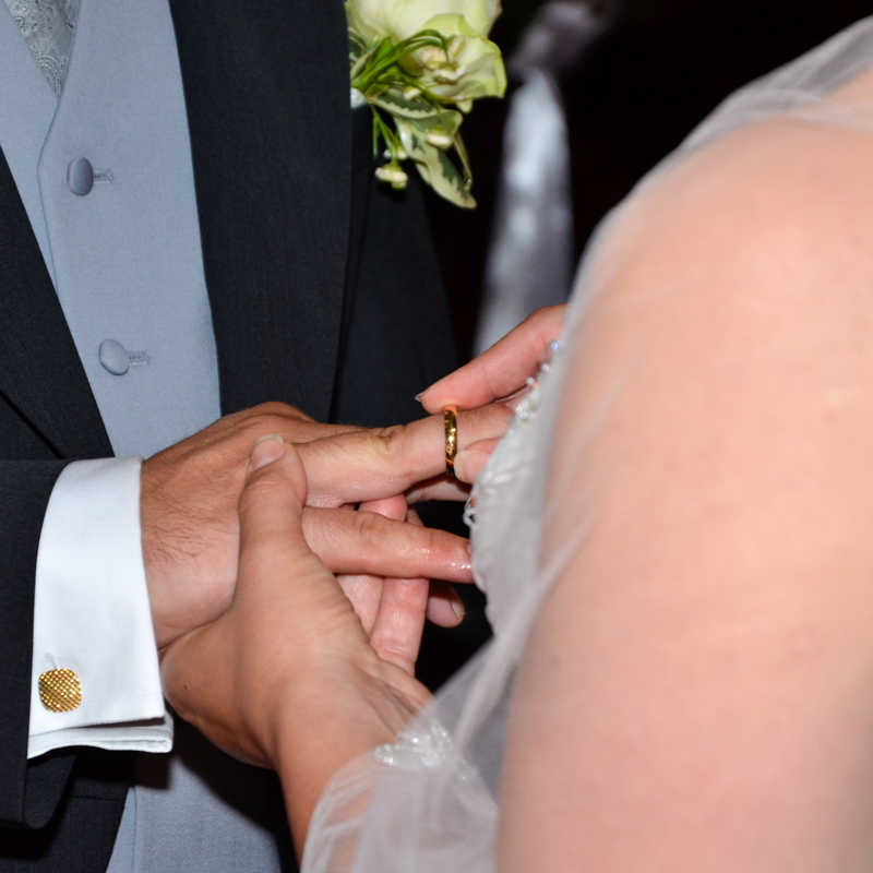 Eine weibliche Hand steckt einen Ring auf den Ringfinger einer männlichen Hand