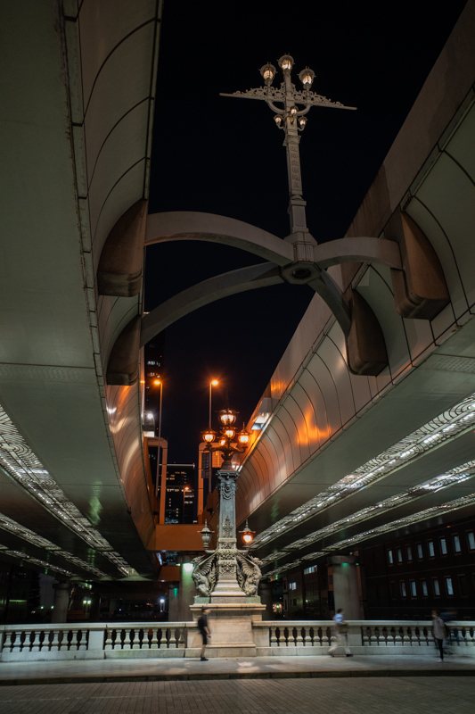 Nachtaufnahme einer Autobahnbrücke oberhalb einer alten Brücke, zwischen den Fahrbahnen der Autobahn und auf der alten Brücke stehen alte aussehende Gusseisen-Laternen